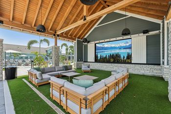 A wooden patio with a couch and a television screen.